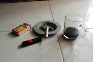 ashtray, cigarette and almost empty coffee cup showing examples of vices