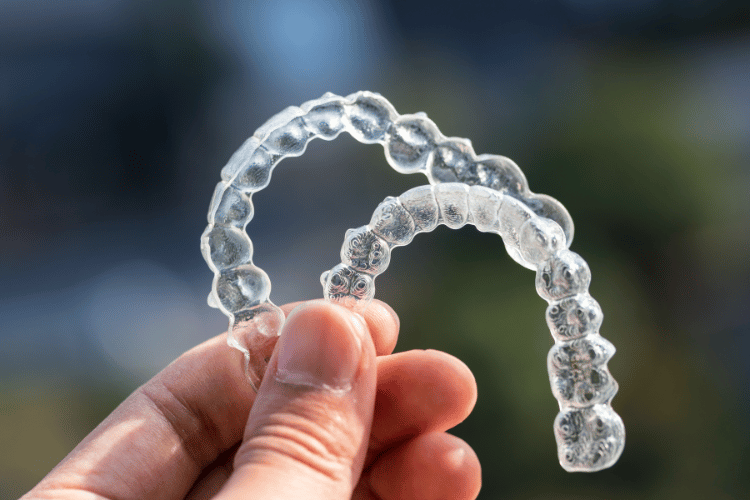 A close-up of a man holding a Invisalign braces