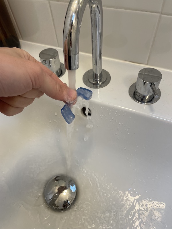 rinsing night guard with water to clean it