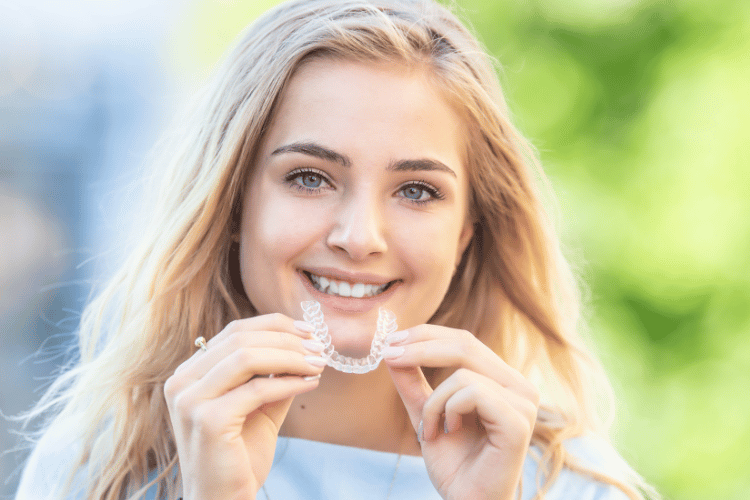 Young smiling woman holding - using invisible braces or trainer