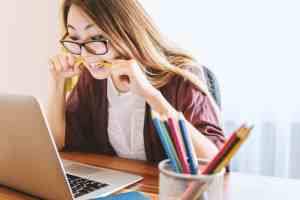 woman at computer biting a pen from stress